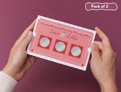 Couple holding a Love Lotto card while enjoying a romantic evening at home with wine and candles.